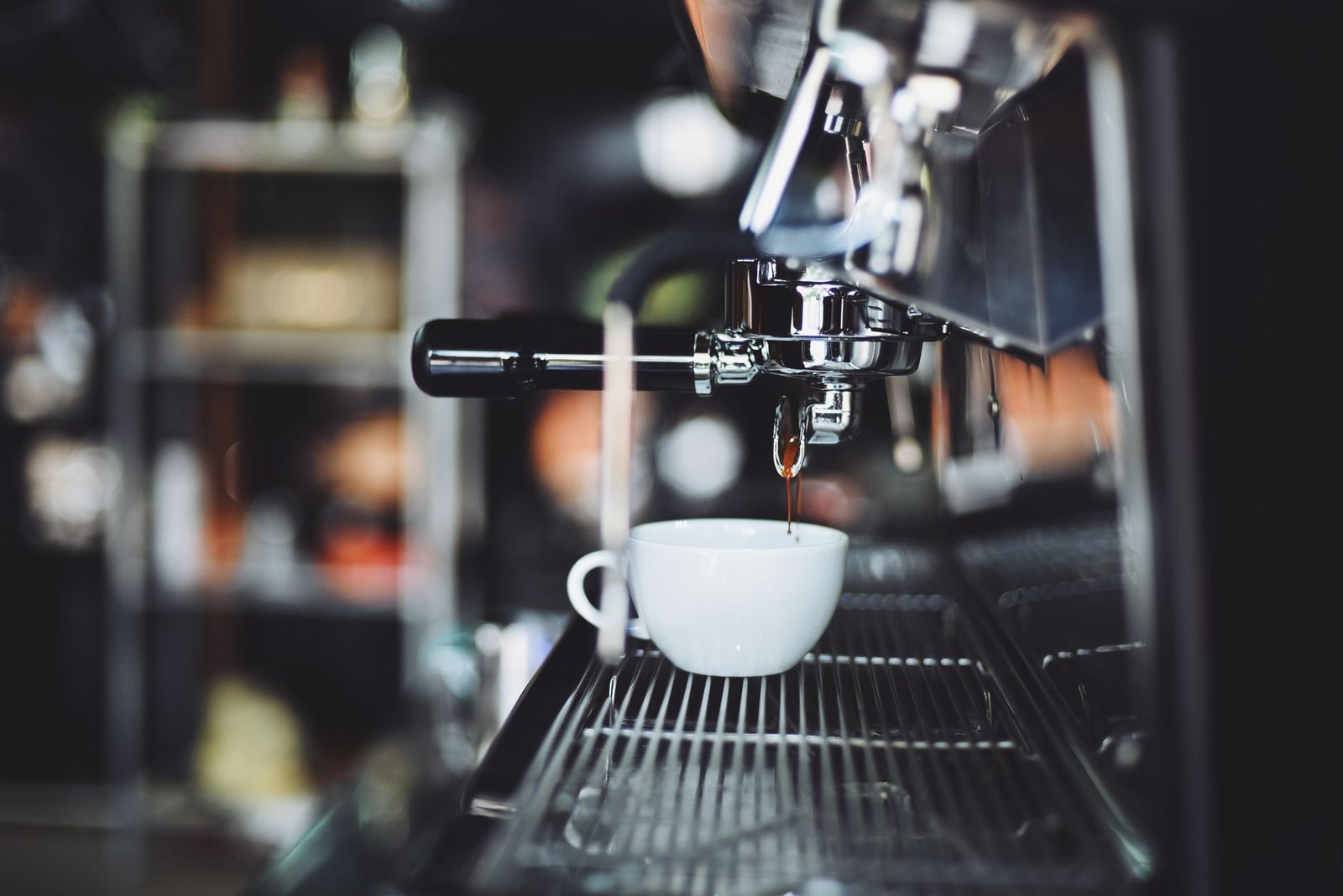 Close-up of espresso machine brewing coffee into a white cup in a cafe setting. (pexels: 302893)